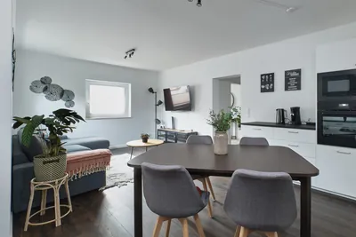 Living room with sofa and Smart TV, open to the dining area, in Landstuhl TLA apartment near Ramstein Air Base